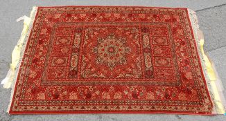 A 20th Century Persian / Islamic rug set on a red background with a central medallion set within a