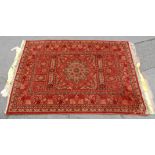A 20th Century Persian / Islamic rug set on a red background with a central medallion set within a