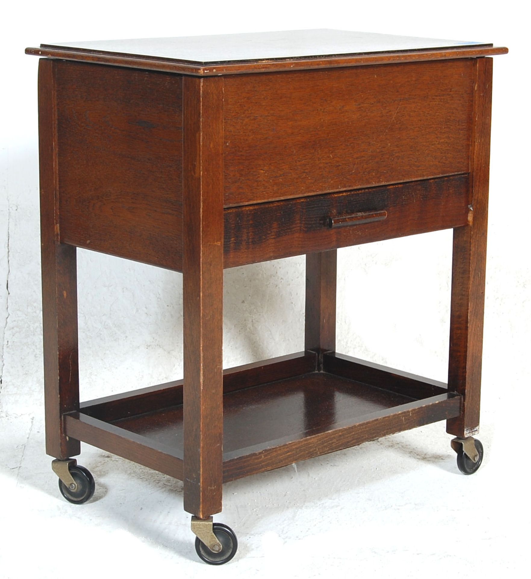 A 1920’s antique oak sewing box with hinged top and inlaid interior over a single drawer with soft