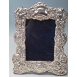 A silver and oak easel backed picture frame decorated with cherubs, puttis, a medieval greenman,
