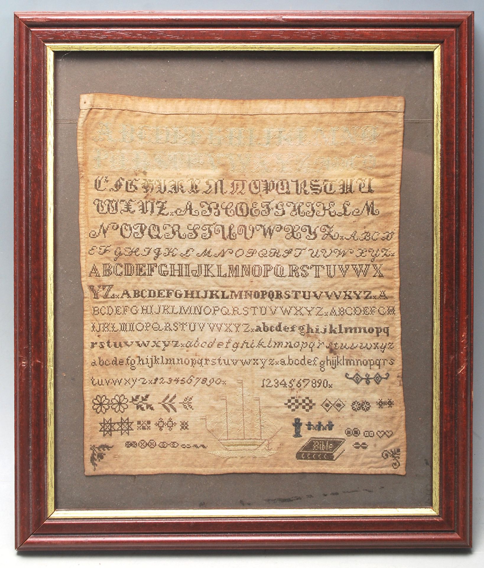 A 19th Century Victorian needlework / needlepoint embroidery sampler stitched with the alphabet,
