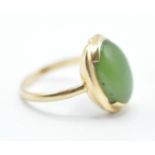 A stamped 14ct gold ring being set with a oval green stone cabochon set within a gold mount.
