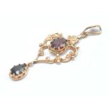 A 20th Century 9ct gold Renaissance style pendant being set with an oval cut red stone and