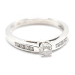 A white gold ladies dress ring having a central diamond of 20 points together with further accent