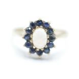 A hallmarked 9ct gold opal and blues stone ring having a central oval opal cabochon with a halo of