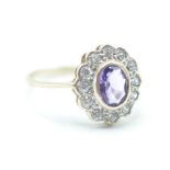 A hallmarked 9ct gold ladies cluster ring having a central oval cut purple stone with a halo of
