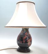 A 20th Century Moorcroft finches pattern table lamp of baluster form being decorated with tube lined