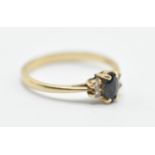 A 14ct gold ring set having a blue oval central stone flanked by four white stone with pierced