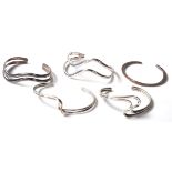 A group of five stamped 925 silver bangles four split design wave shaped bangle and one of plain