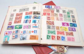 A collection of vintage 20th Century world stamps in red albums dating from the early 20th Century