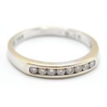 A hallmarked 18ct white gold ring being channel set with eight round cut diamonds. Hallmarked