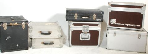 A group of seven music equipment carry case with most being flight cases and some bearing makers