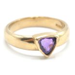 A hallmarked 9ct gold old band ring being bezel set with a triangular cut purple stone. Hallmarked