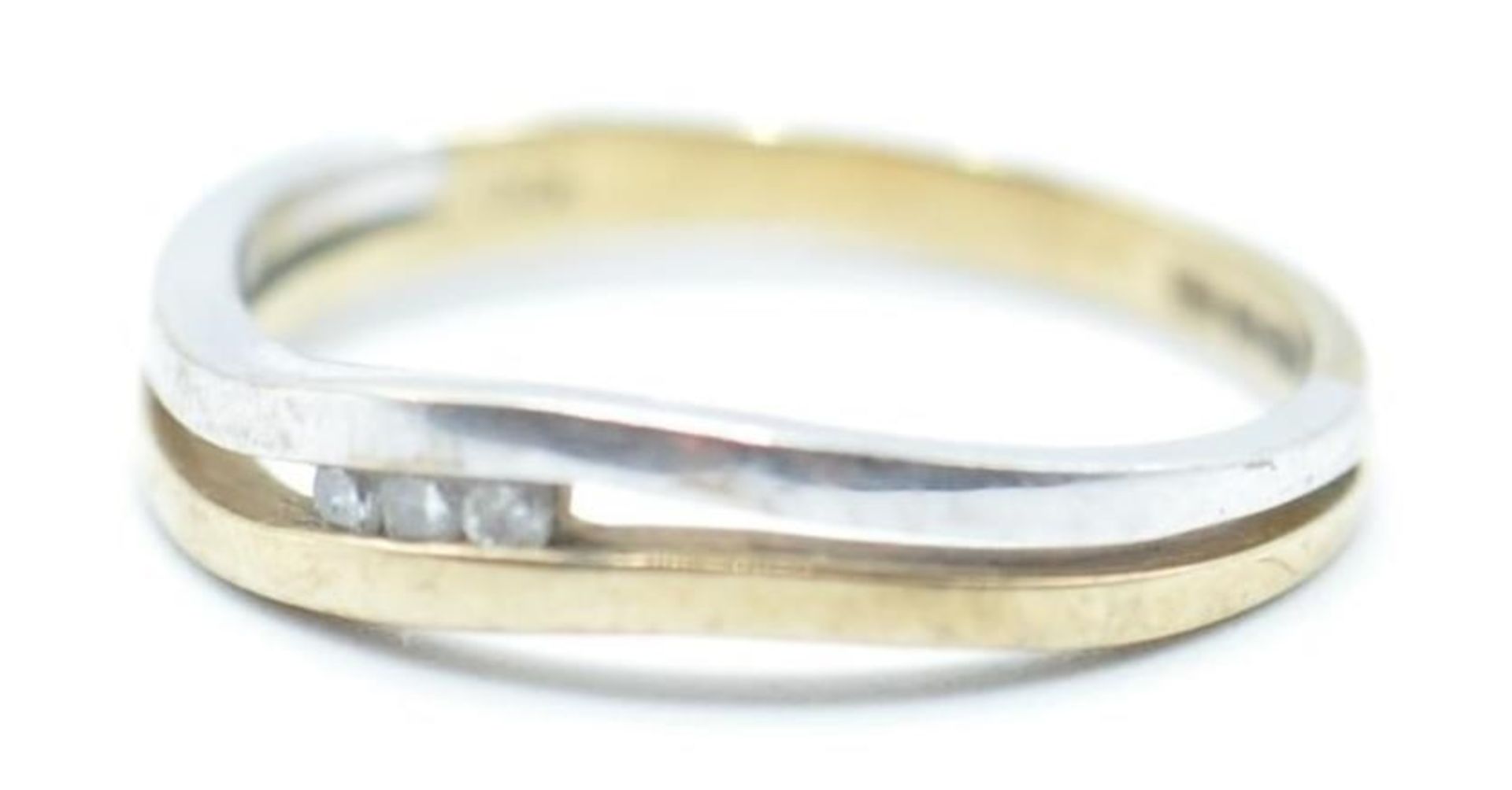 A hallmarked 9ct gold two tone split band ring set with three round cut diamonds. Hallmarked