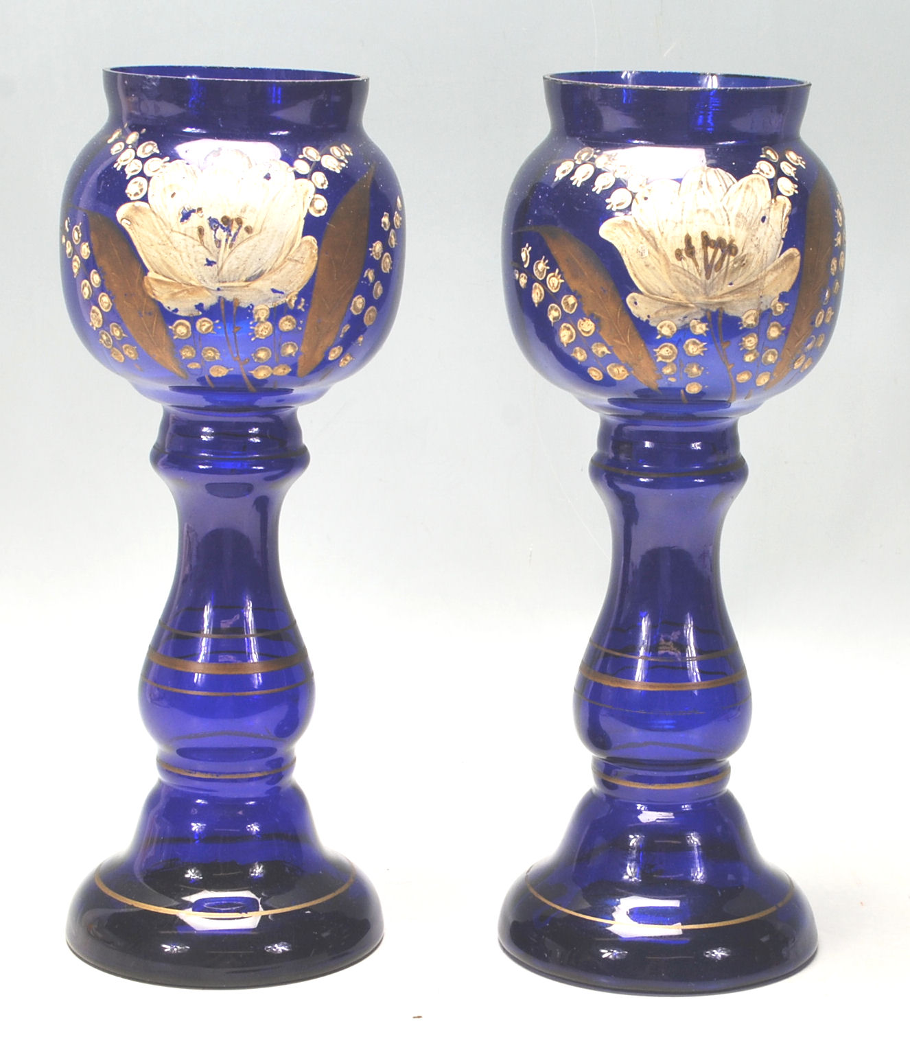 A pair of early 20th Century Bristol Blue vases hand painted with flowers and gilded detailing.