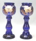A pair of early 20th Century Bristol Blue vases hand painted with flowers and gilded detailing.