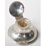 A silver hallmarked ink well of round form having a domed hinge lid to the top opening to reveal a