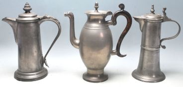 A group of three 19th century pewter jugs having hinged lid with spouted decoration atop.