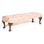 A 19th century George III long oak footstool ottoman being upholstered in a  red floral upholstery