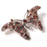 An Art Nouveau style stamped sterling silver and garnet pinback brooch in the form of a butterfly.