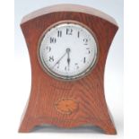 An early 20th Century French oak mantel / mantle clock having a round white enamelled face with