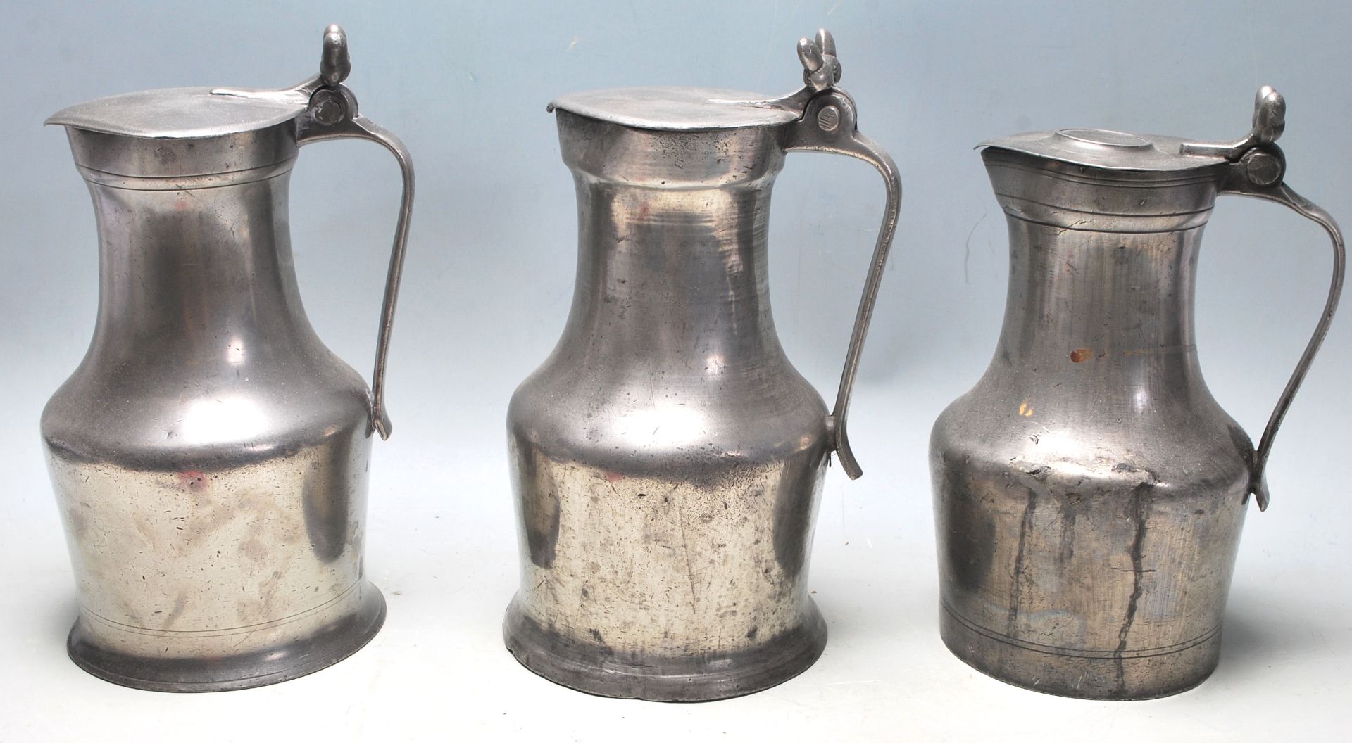 Three large 19th century pewter jugs having hinged lid with acorn decoration