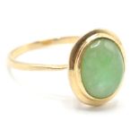 A stamped 585 14ct gold ring being set with an oval jade cabochon in a bezel setting. Weight 2.8g.