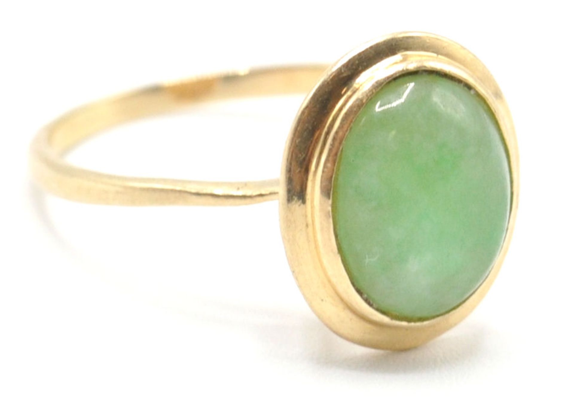 A stamped 585 14ct gold ring being set with an oval jade cabochon in a bezel setting. Weight 2.8g.