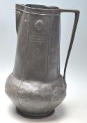 A early 20th century Art Nouveau pewter jug with tapered handle, bulbous form, sea shell raised