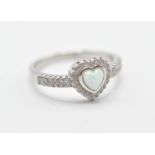 A stamped .925 silver ladies dress ring having a heart shaped opal set within a halo of accent
