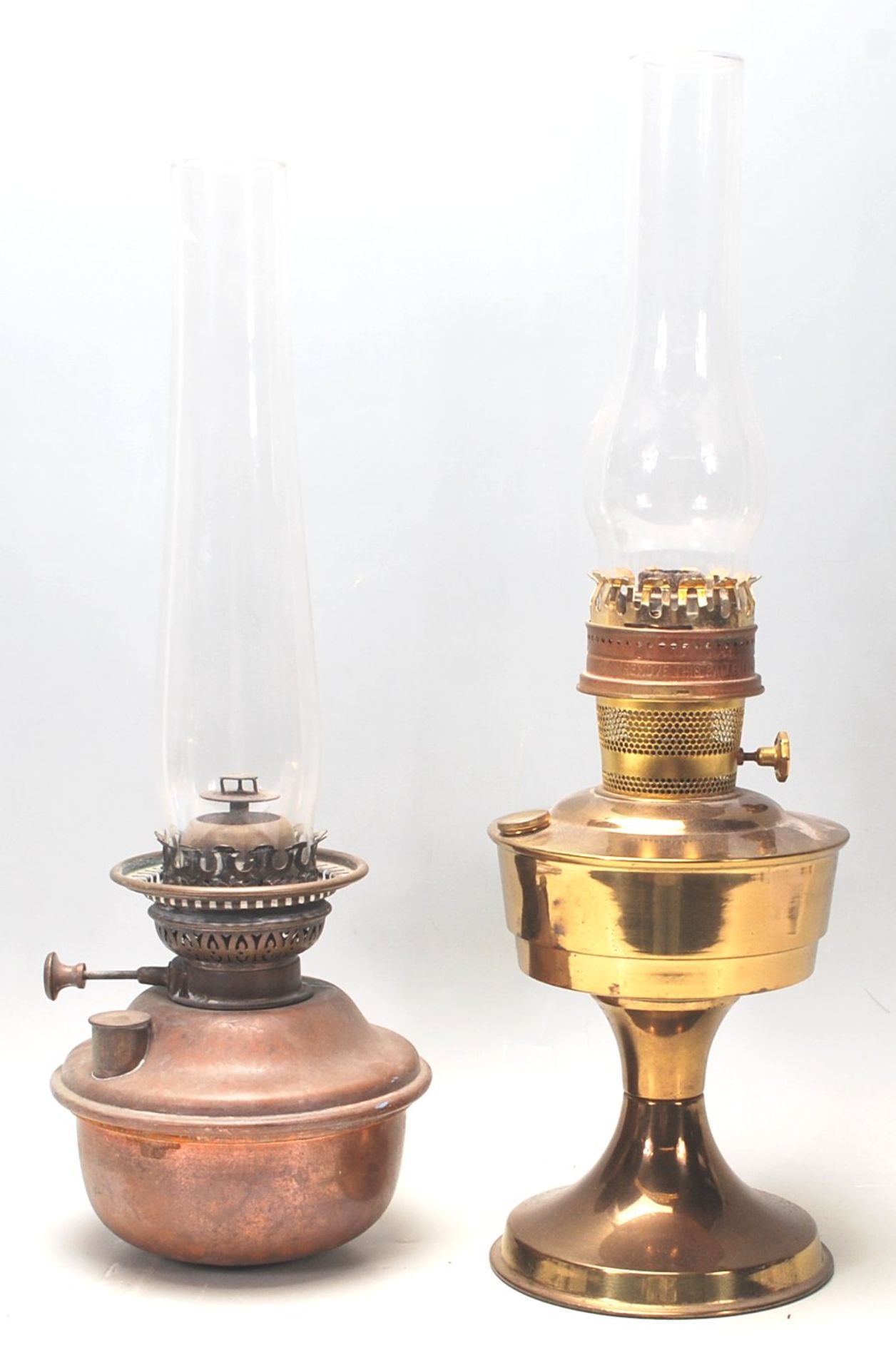 A pair of early 20th century brass oil lamps, one set on a circular base, both complete with glass