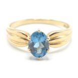 A stamped 375 9ct gold ladies dress ring being set with an oval cut blue stone with pinched reeded