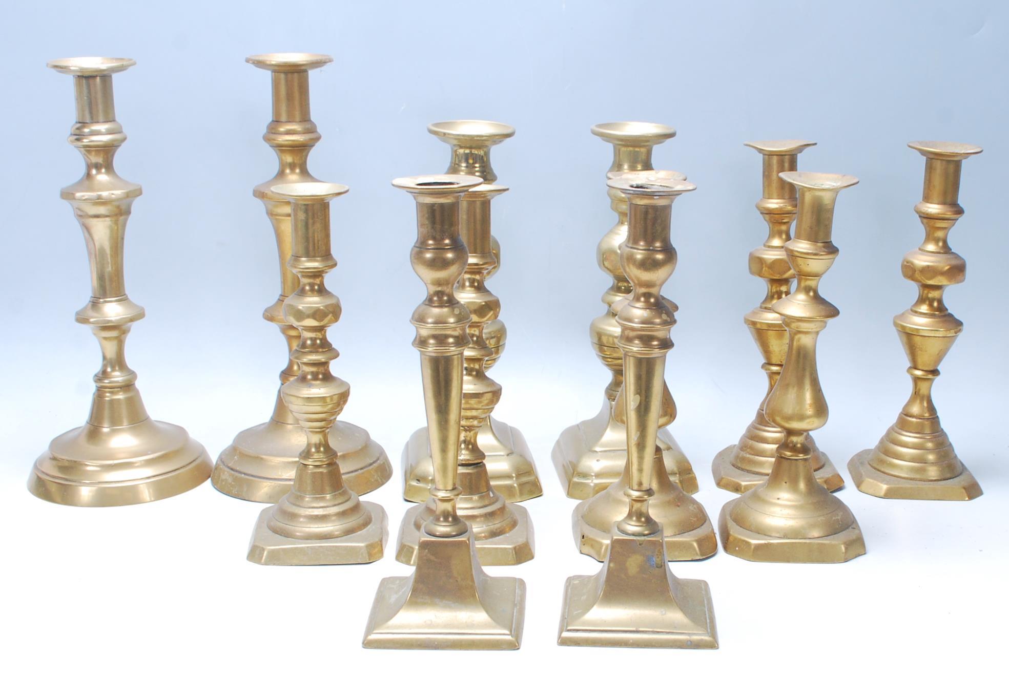 An early 20th / late 19th Century set of six tabletop brass candlesticks being raised on a squared