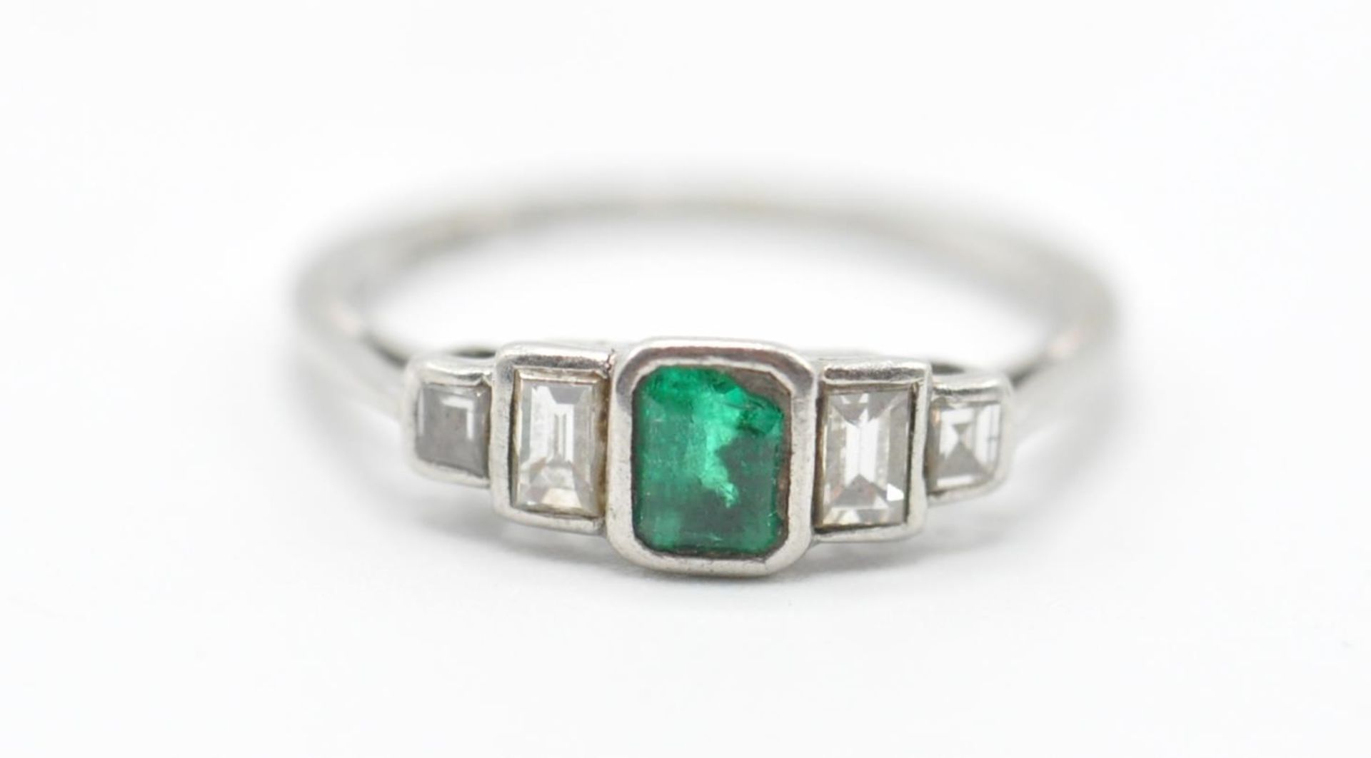 A platinum, emerald and diamonds ring having a central rectangular cut emerald flanked by four