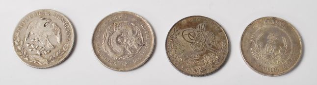 A group of four silver world coins to include a Memento Birth of Republic of China silver coin, a