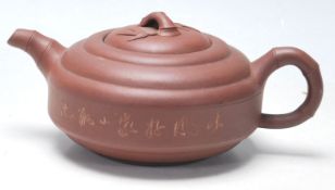 A 20th Century Chinese red clay Yi Xing teapot of round stepped form having a bamboo formed spout