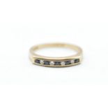 A hallmarked 9ct gold ring being channel set with alternate blue and white stones. Hallmarked