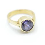 A hallmarked 18ct gold ring bezel set with a round cut purple stone. Stone measures approx 8mm