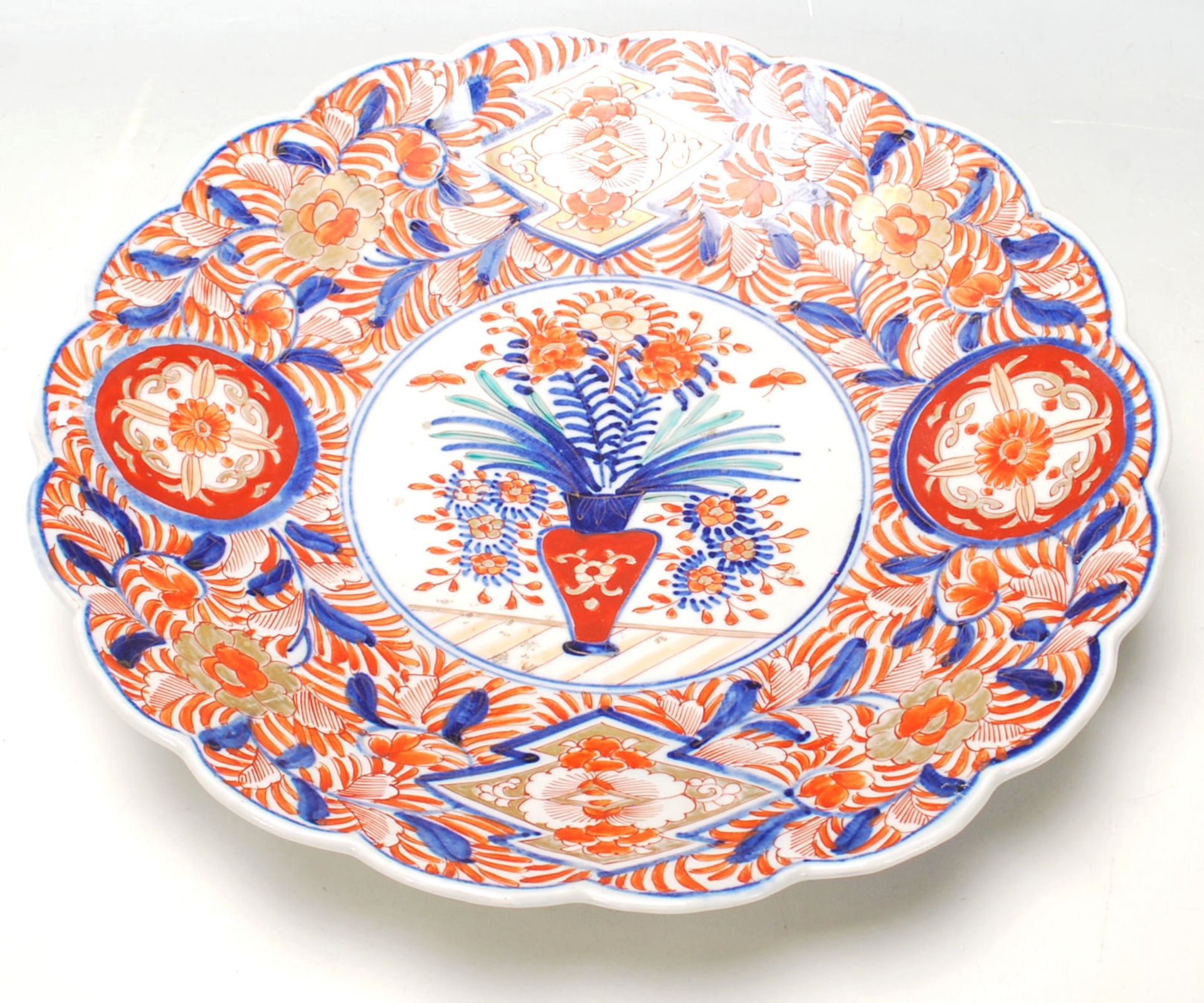 A 19th Century Japanese Imari charger plate with scalloped rim, typical decoration with a vase of