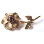 A 9ct gold brooch in the form of a flower being set with six round cut red stones with a hinge to