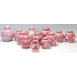 A collection of thirteen 20th Century Chinese famille rose ginger jars being decorated with red
