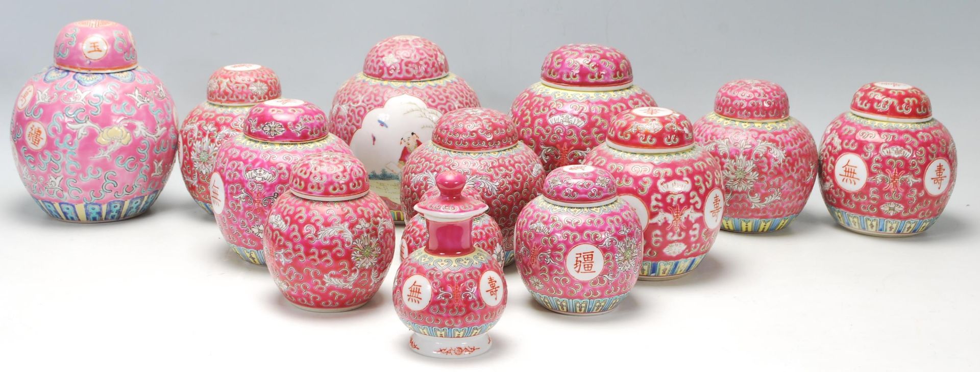 A collection of thirteen 20th Century Chinese famille rose ginger jars being decorated with red