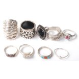 A collection of nine silver rings to include a crossover ring set with three round cut white stones,