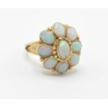 An 18ct gold lady’s dress ring having a flower head set with nine oval opal cabochons with pierced