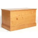 An antique style 20th century country pine blanket box with hinged lid opening to reveal storage