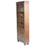 A 1920’s Arts & Crafts oak tall library bookcase cabinet with adjustable shelves, twin leaded and