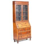 A 1920's Jacobean revival oak bureau bookcase with twin leaded and glazed doors having adjustable