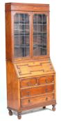 A 1920's Jacobean revival oak bureau bookcase with twin leaded and glazed doors having adjustable