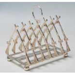 An unusual silver plated toast rack having a hoop carry handle over crossed rifle shaped