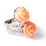 A stamped .925 silver crossover ladies dress ring having a twin flower shaped coral stone with CZ